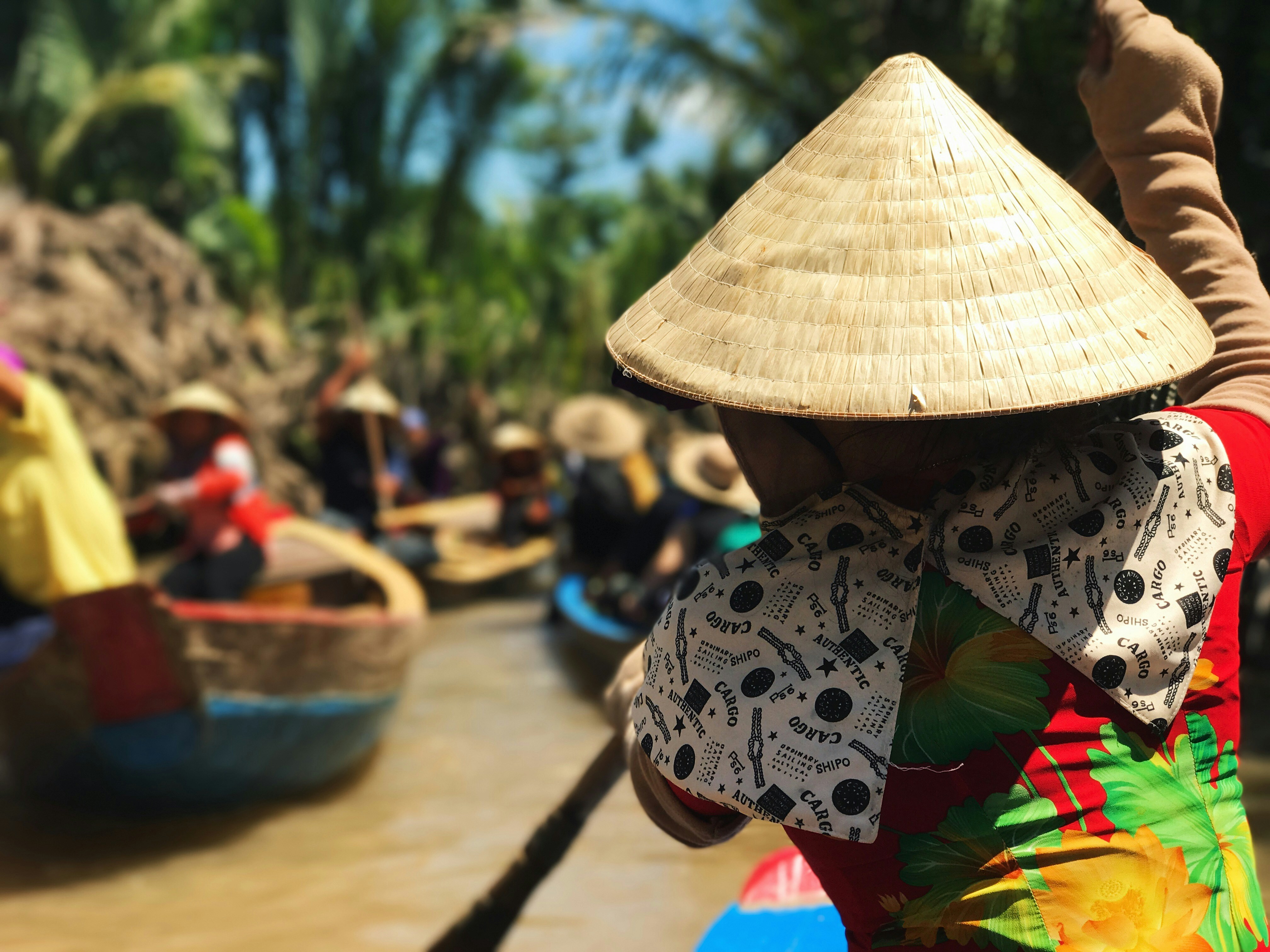 Rower in a conical hat guiding a basket boat through the delta