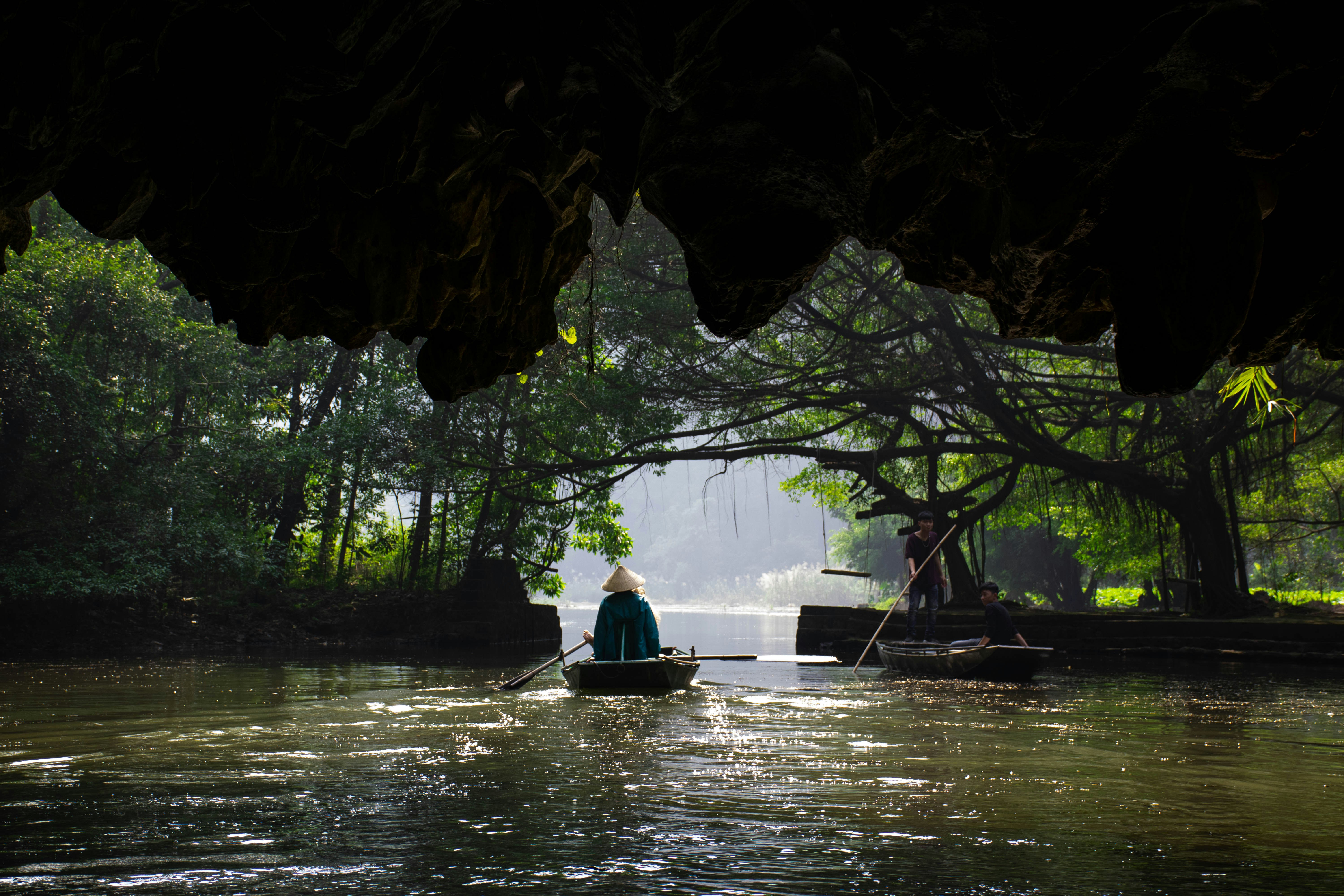Rowboats drifting out of a river cave