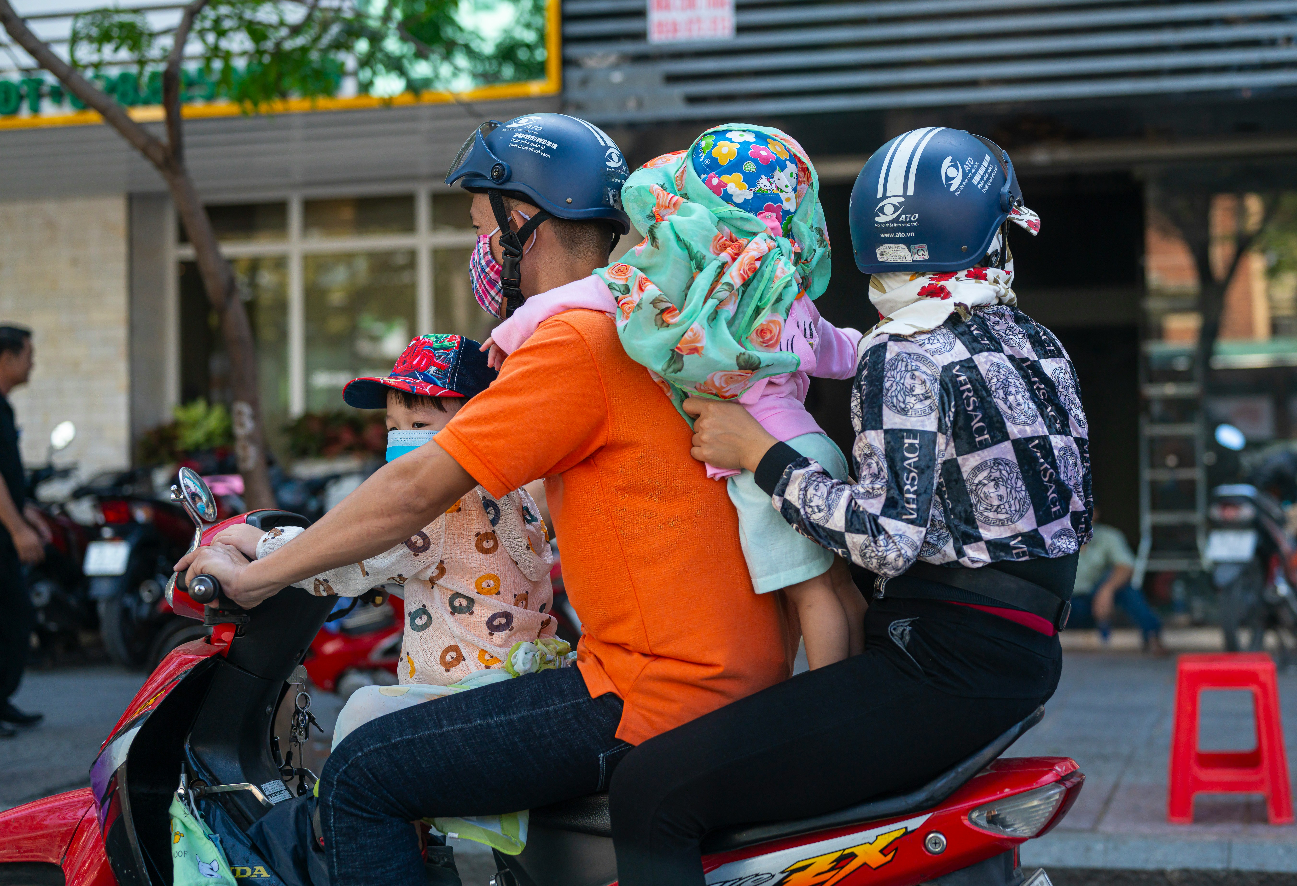 A family of four riding one scooter through the city